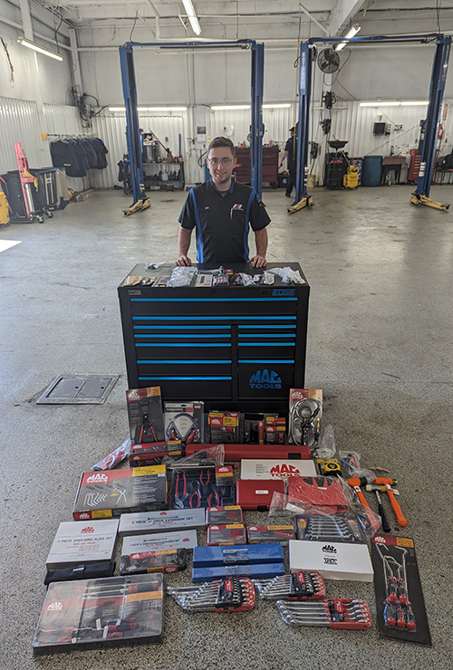 SCADT Apprentice standing behind the tool box and tools received through the scholarship